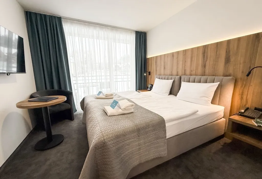 Pokój dwuosobowy Superior w Solina Resort w Polańczyku z dużym łóżkiem, drewnianą ścianą i szerokim oknem