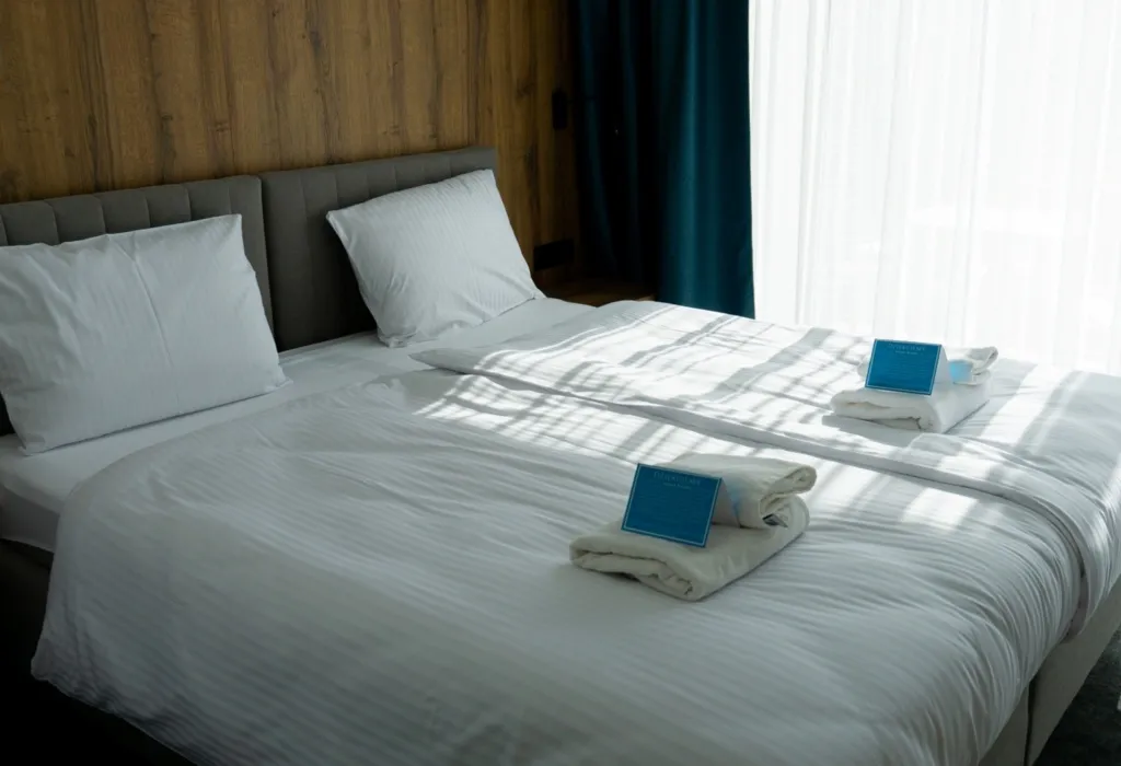Łóżka z ręcznikami i okno z zasłonami w pokoju hotelowym Solina Resort