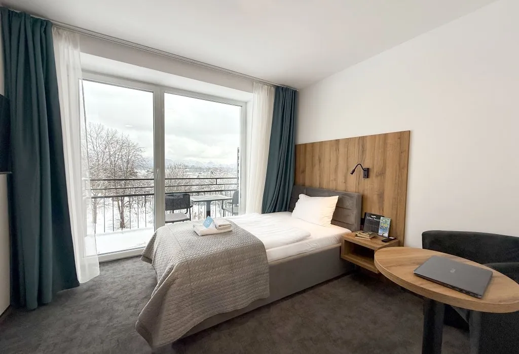 Pokój w Solina Resort z balkonem i zimowym krajobrazem za przeszklonymi drzwiami