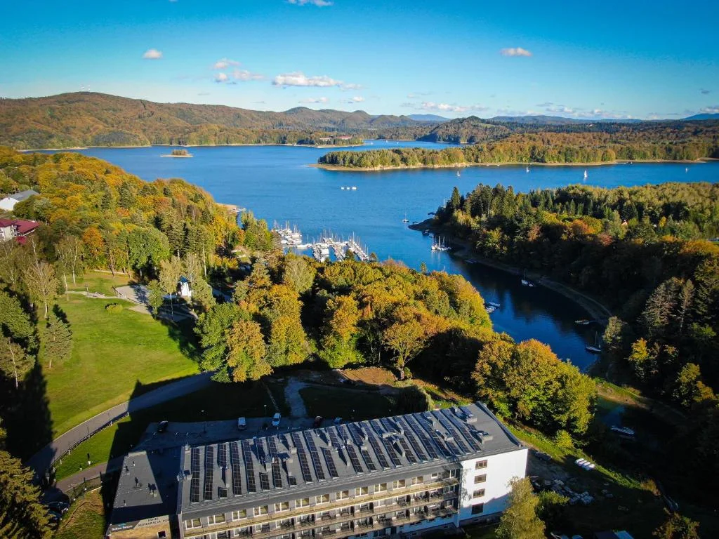 Solina Resort z lotu ptaka: budynek hotelu z panelami słonecznymi, przystań i jesienne Jezioro Solińskie